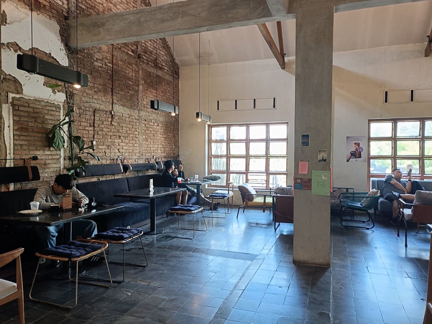 Exposed-brick interior of Monday Co Dago, customers working at heritage tables